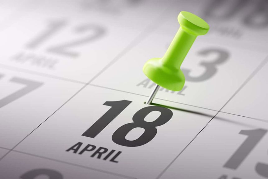 closeup of lime green thumbtack on calendar date of April 18